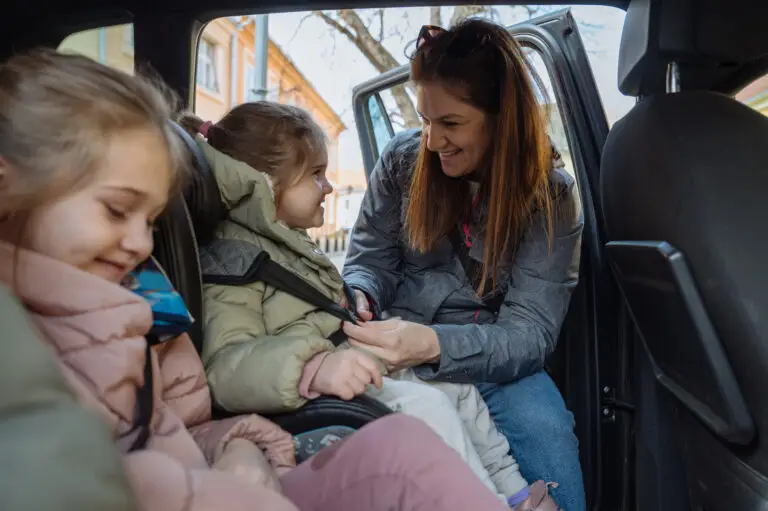 Mother securing car service car seat on her baby child in NYC